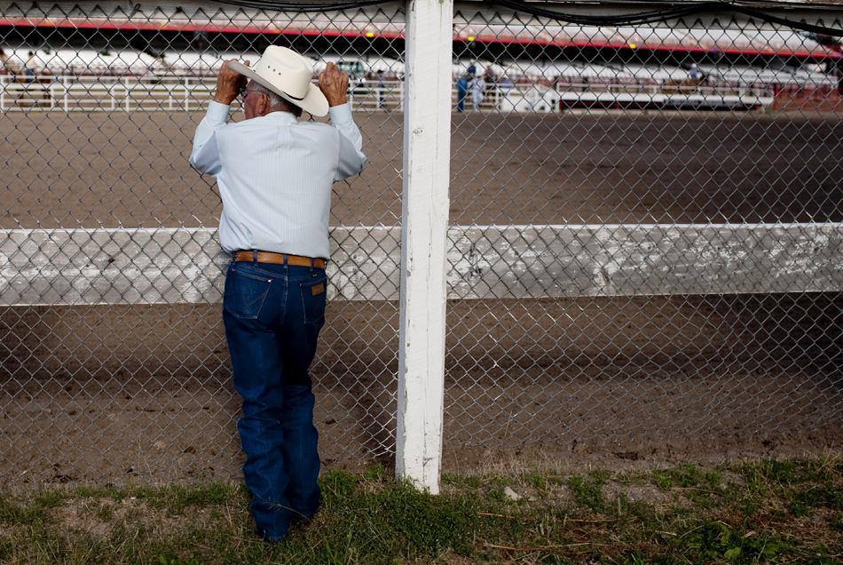 A spectator watches the action from behind a fence during the first go of slack tie-down roping on Wednesday, July 20, 2011, at Frontier Park.