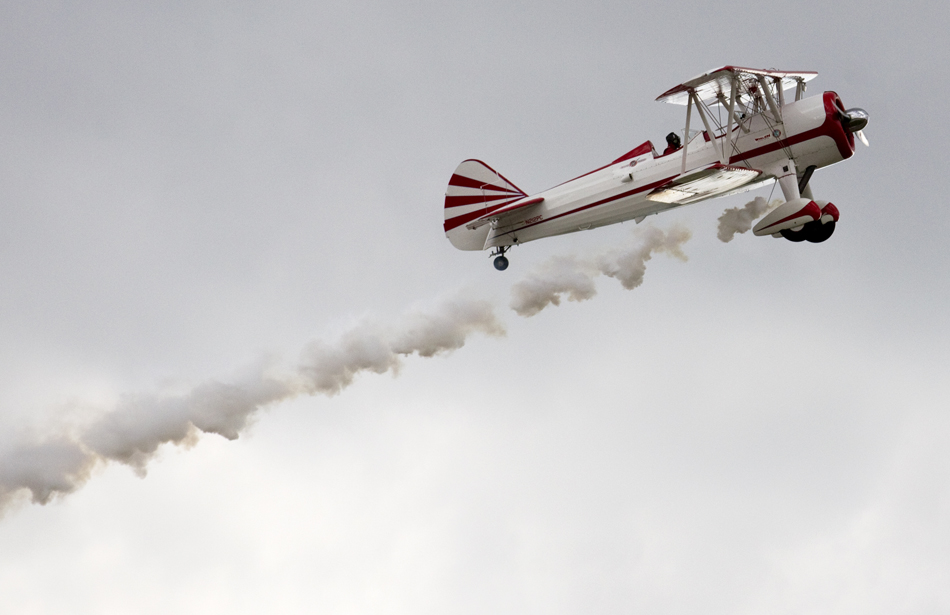 A vintage biplane soars above the crowd letting out smoke as it performs during an air show on Wednesday, July 27, 2011, at the Wyoming Air National Guard base in Cheyenne.