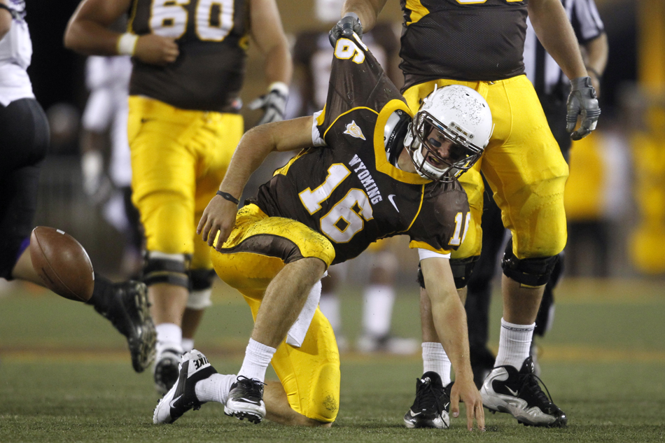 Wyoming offensive tackle John Hutchins picks up quarterback Brett Smith after Smith was sacked during a NCAA college football game on Saturday, Sept. 3, 2011, at War Memorial Stadium in Laramie, Wyo.