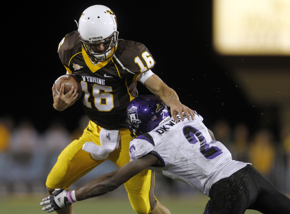 Wyoming quarterback Brett Smith sheds off Weber State safety Willie Okwuonu as Smith runs for a big gain during a NCAA college football game on Saturday, Sept. 3, 2011, at War Memorial Stadium in Laramie, Wyo.