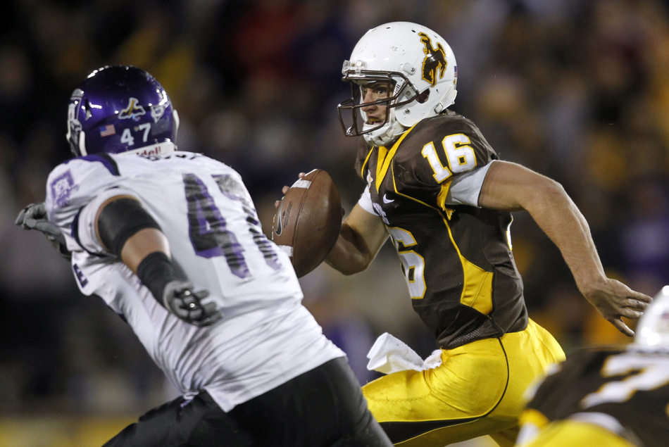 Wyoming quarterback Brett Smith scrambles away from pressure applied by Weber State defensive end Gabe Bowers during a NCAA college football game on Saturday, Sept. 3, 2011, at War Memorial Stadium in Laramie, Wyo.