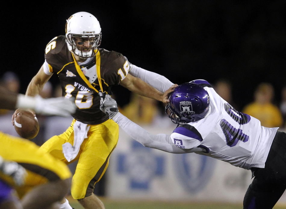 Wyoming quarterback Brett Smith tries to shed off Weber State defensive end Caldwell Taylor during a NCAA college football game on Saturday, Sept. 3, 2011, at War Memorial Stadium in Laramie, Wyo.
