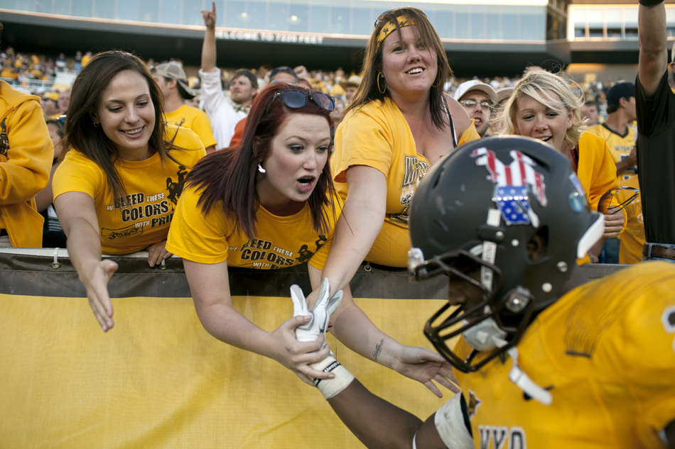Fans high five Wyoming running back Ghaali Muhammad during a NCAA college football game on Saturday, Sept. 10, 2011, at War Memorial Stadium in Laramie, Wyo.