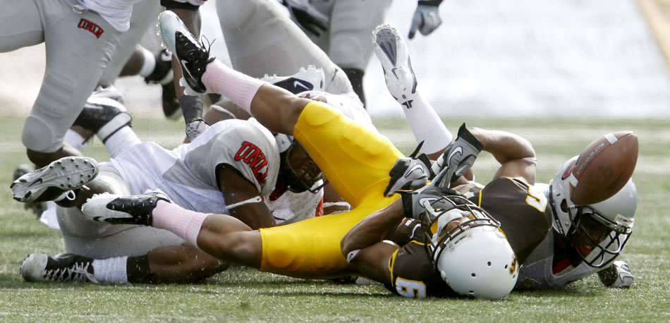 UNLV defenders scramble for a fumble from Wyoming wide receiver Robert Herron during a NCAA college football game on Saturday, Oct. 15, 2011, in Laramie, Wyo.