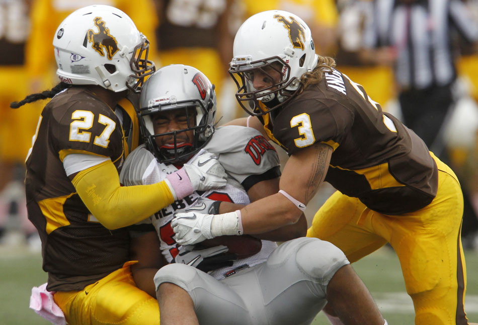 Wyoming linebacker Todd Knight (27) and safety Luke Anderson (3) wrap up UNLV running back Dionza Bradford for a loss during a NCAA college football game on Saturday, Oct. 15, 2011, in Laramie, Wyo.