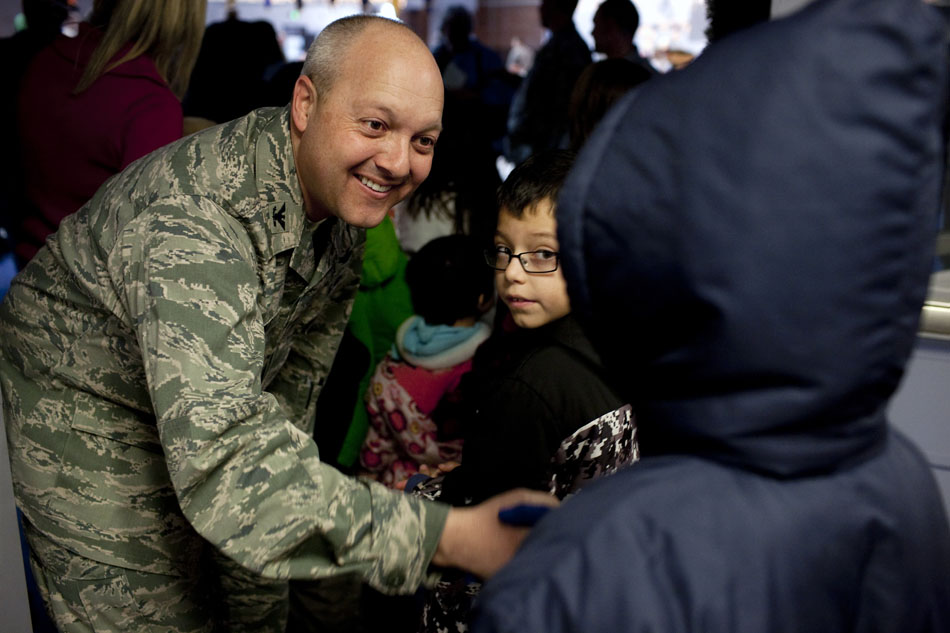 Col. Chris "Boots" Coffelt, commander of the 90th Missile Wing at F.E. Warren Air Force Base, shakes hands with one of 116 children as they make their way into Operation Provide Joy on Saturday, Dec. 10, 2011, at the base in Cheyenne. Each child was pared with a service member from the base and partook in games and crafts.