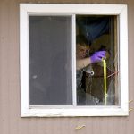 A crime scene technician takes a measurement in a window of a mobile home that appears to have been broken by a bullet on Friday, July 8, 2011, at 757 E. Oak St. #19 in Wheatland, Wyo. Wheatland police arrested Everett Conant III at the home Thursday evening after a shooting that left four people dead and one injured. The yellow and magenta sticks protruding from the building are commonly used to determine bullet trajectories in crime scene investigations. (James Brosher/Wyoming Tribune Eagle)