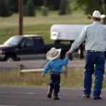 A man crosses the road with his youngster after a chuckwagon breakfast before the Cheyenne Frontier Days cattle drive on Sunday, July 17, 2011, in Cheyenne. (James Brosher/Wyoming Tribune Eagle)