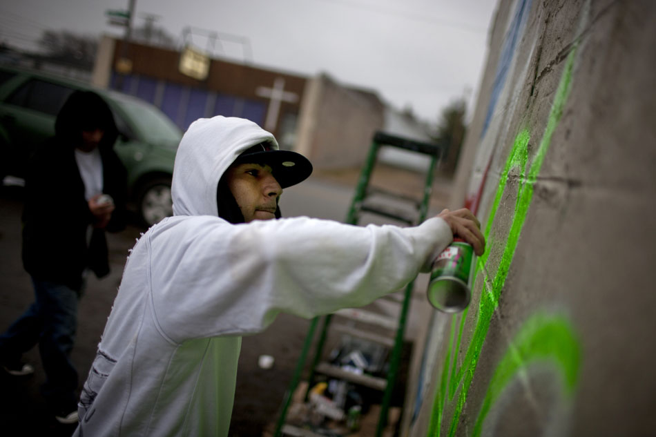 Isaro Simental adds green to the word "side" as he and Sammy Aguire, background, paint a mural on the side of the Little Mexico West Side Barbershop on Tuesday, Feb. 21, 2012, along Western Avenue in South Bend. Simental, who is also a barber at the shop, and Aguire had been working on the mural for about two hours by 3:30 p.m. Tuesday afternoon, but had already completed a barber's pole that spanned the height of the building's east side. (James Brosher/South Bend Tribune)