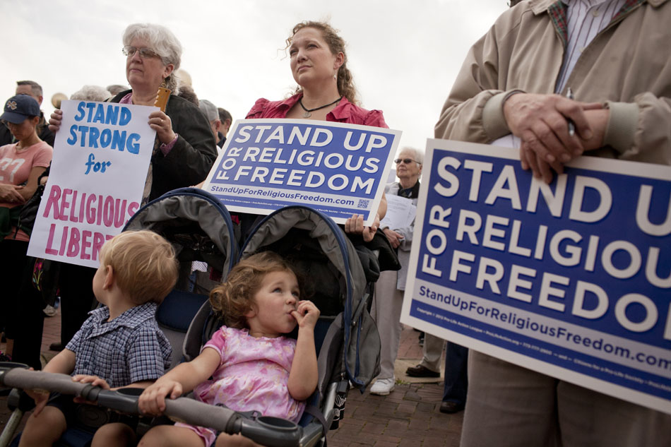 Alicia Nagy, center, listens to a speaker with her children Julia, 3, and John Bosco, 1, during the Rally for Religious Freedom on Friday, March 23, 2012, on Jon R. Hunt Plaza in downtown South Bend. (James Brosher/South Bend Tribune)