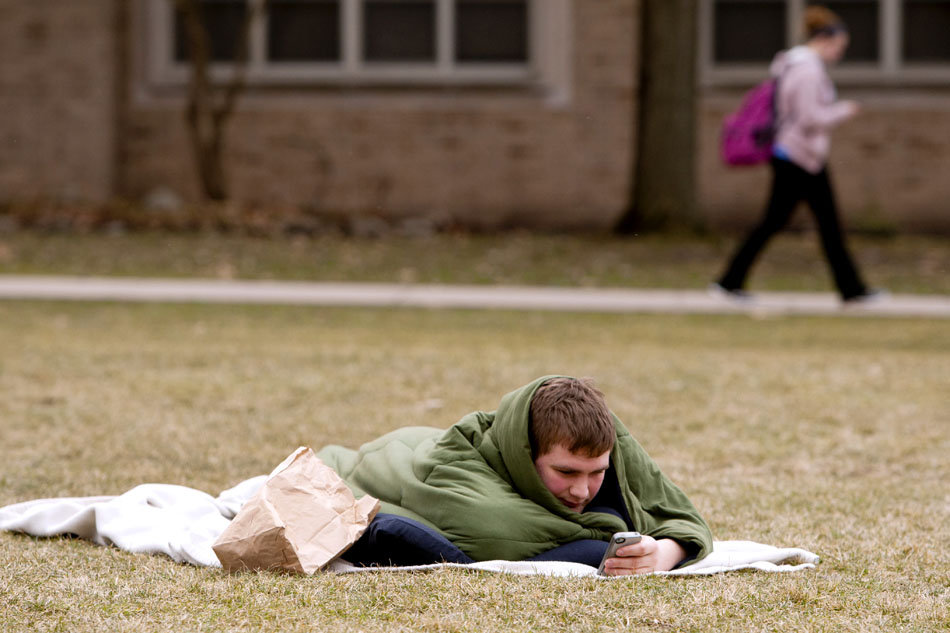 Joe Dolan, a sophomore from Fishers, Ind., checks his iPhone as he lays under a cocoon of blankets on Wednesday, March 7, 2012, on a grassy area in front of Fisher Hall on the Notre Dame campus. Dolan said he had been laying out since about 8 a.m. and planned to do so until a class at 4 p.m. (James Brosher/South Bend Tribune)