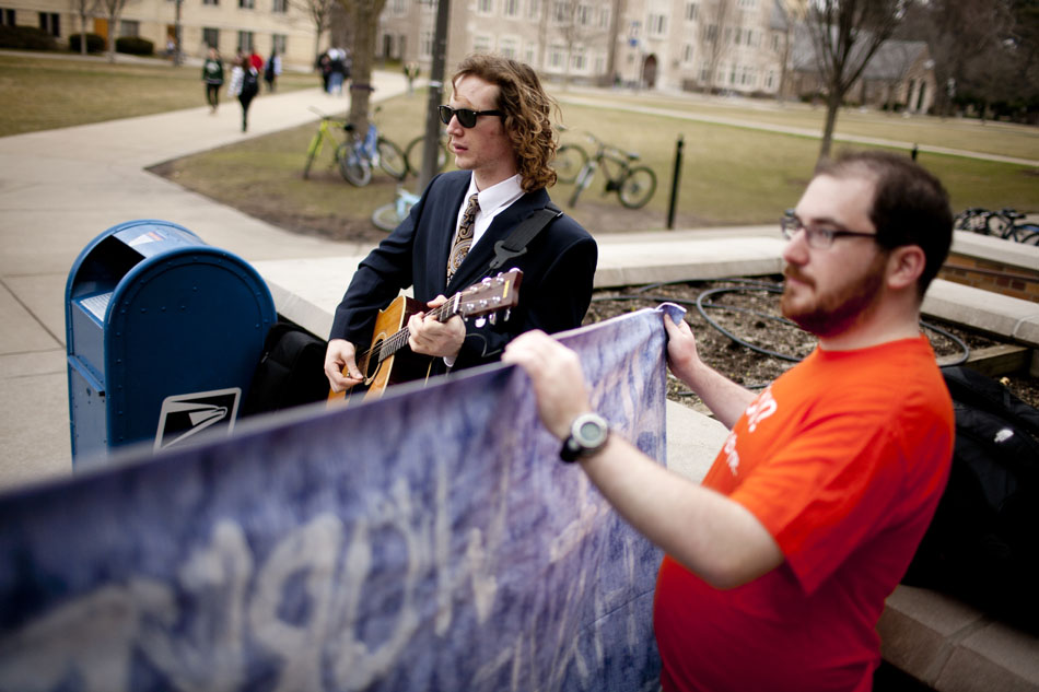 Taylor Nutter, left, a sophomore, plays the guitar as he protests against HEI, a hotel management company, with Ryan O'Laughlin, a senior, on Wednesday, March 7, 2012, outside Notre Dame's South Dining Hall. The students marched across campus with the banner and guitar to protest what they see as HEI's abuse of worker rights. (James Brosher/South Bend Tribune)