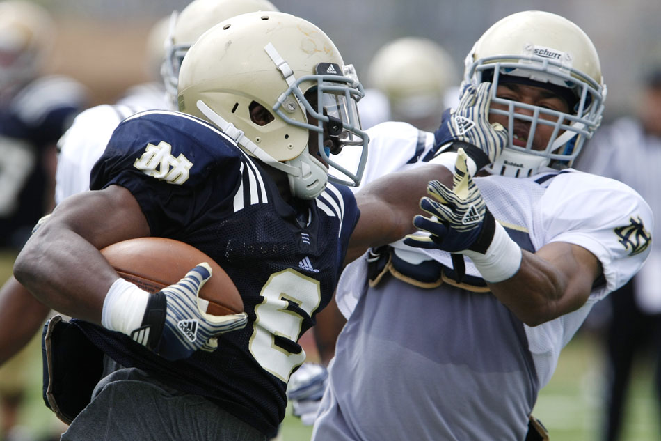 Notre Dame running back Theo Riddick stiff arms cornerback Josh Atkinson during a spring football practice on Saturday, March 24, 2012, at the LaBar practice fields. (James Brosher/South Bend Tribune)