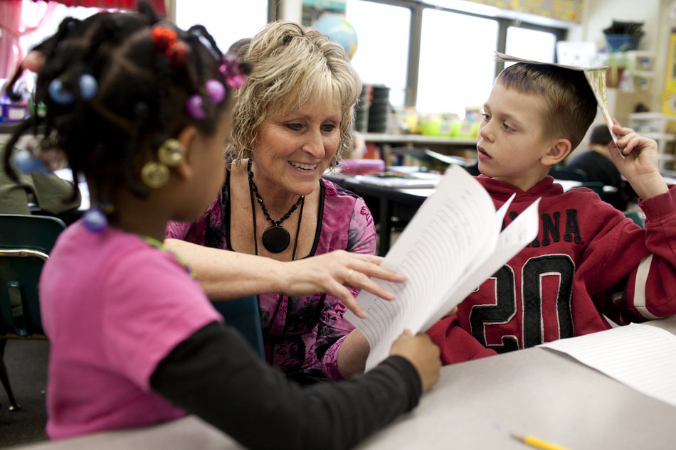 Jeanine Reynolds, a second-grade teacher at Emmons Elementary, smiles as she looks over work from Nykeria Harper, left, and Riley Penrod during a free-write session on Wednesday, Feb. 29, 2012, in Mishawaka. (James Brosher/South Bend Tribune)