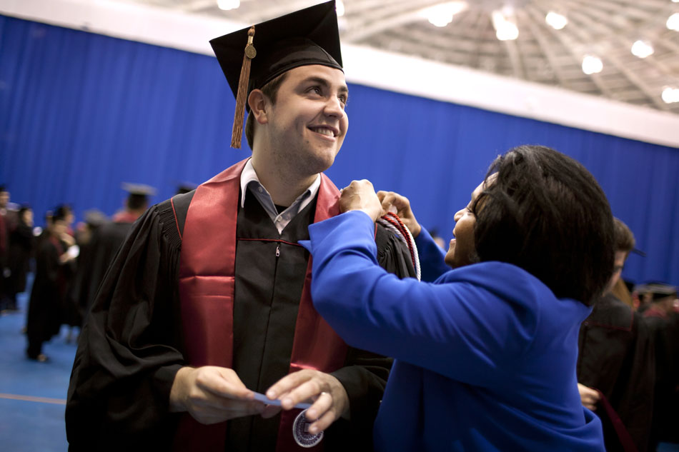 Todd Martin gets a hand from Patricia Agbetsiafa, director of administrative and student services at the IU-South Bend School of Business and Economics before Indiana University-South Bend commencement exercises on Tuesday, May 8, 2012, in the Purcell Pavilion at Notre Dame. (James Brosher/South Bend Tribune)