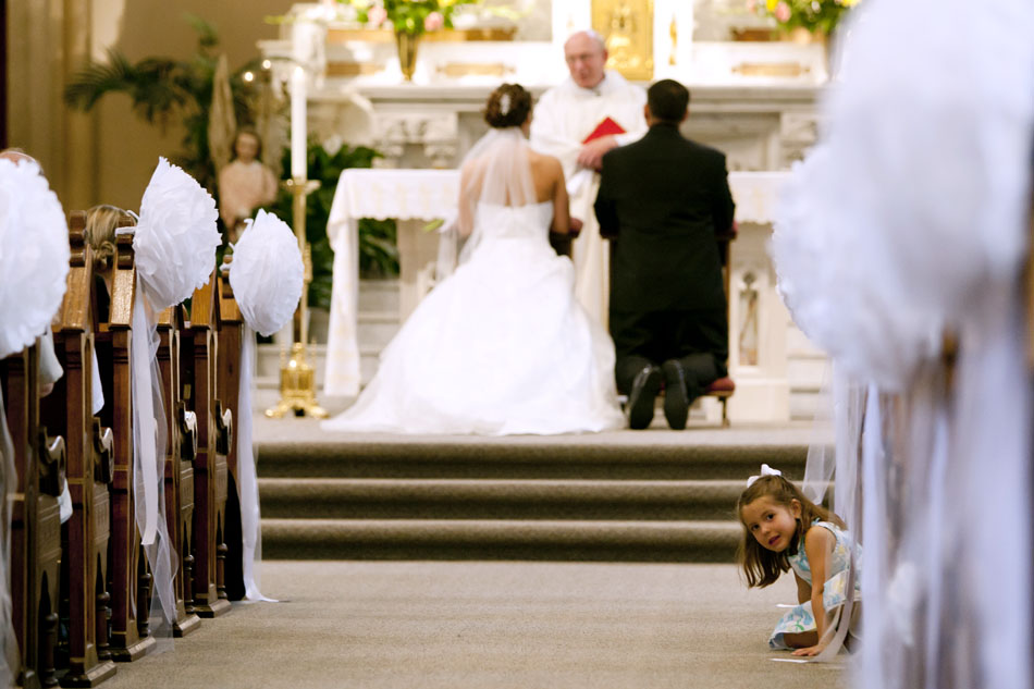 Piper Swart, niece of the groom Alfredo Alvarado, peeks back down the aisle from a pew near the front of the church during a wedding ceremony on Saturday, June 16, 2012, at St. Joseph Parish in Mishawaka. (James Brosher/South Bend Tribune)