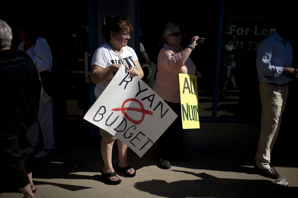 Protestors hold signs protesting a proposed Republican budget written by Rep. Paul Ryan, R-Wisc., during a "Nuns on the Bus" stop on Friday, June 22, 2012, outside of offices of Rep. Joe Donnelly, D-Granger, along Colfax Avenue in South Bend. The bus tour organizers take issue with Ryan's citing his Catholic faith as a justification for large cuts in federal social programs. (James Brosher/South Bend Tribune)