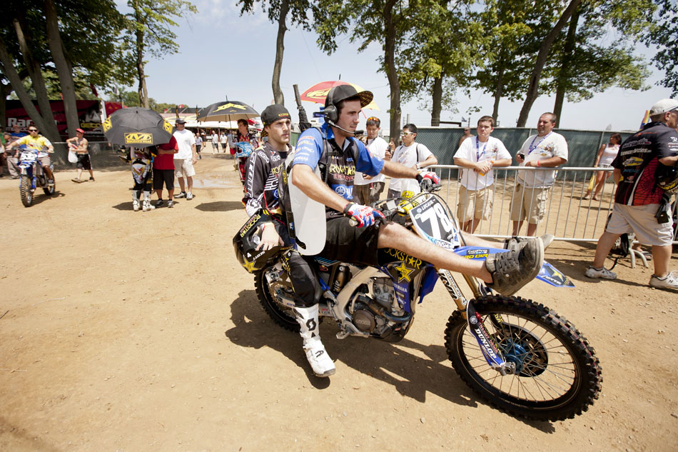A crew member catches a ride with Tommy Weeck, left, before the 250 motocross race at the Red Bull Redbud National on Saturday, July 7, 2012, in Buchanan, Mich. (James Brosher/South Bend Tribune)