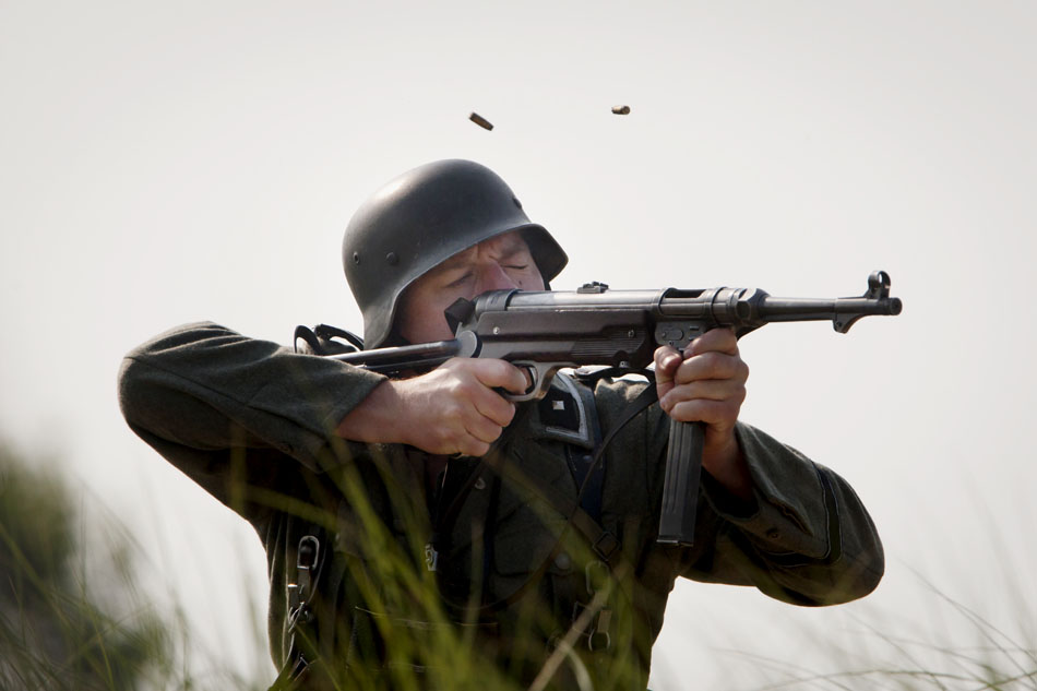 Shell casings eject from a MP 40 Schmeisser submachine gun as a German re-enactor fires at Allied invaders during a WWII re-enactment on Saturday, June 30, 2012, at Tiscornia Beach in St. Joseph, Mich. (James Brosher/South Bend Tribune)