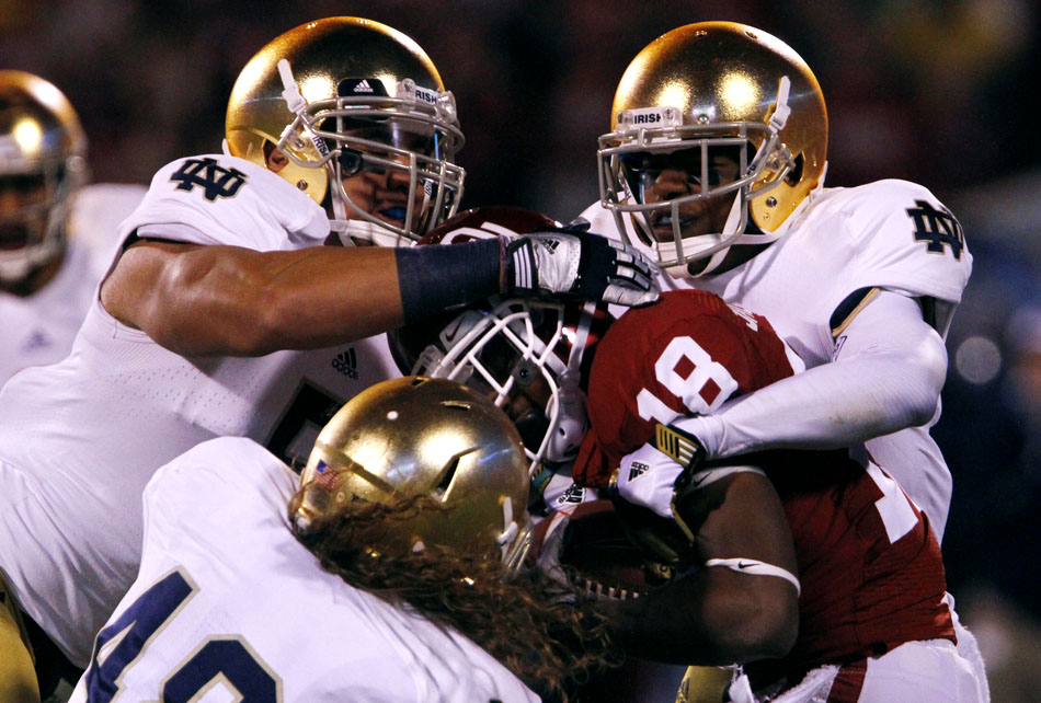 Notre Dame linebacker Manti Te'o, left, cornerback KeiVarae Russell, right, and linebacker Dan Fox tackle Oklahoma wide receiver Lacoltan Bester (18) during an NCAA college football game on Saturday, Oct. 27, 2012, in Norman, Okla. (James Brosher/South Bend Tribune)