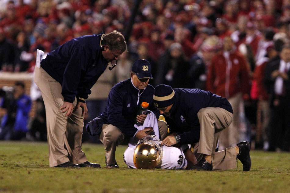 Notre Dame head coach Brian Kelly, left, watches as medical staff members check out quarterback Everett Golson after he was injured on a play during an NCAA college football game on Saturday, Oct. 27, 2012, in Norman, Okla. (James Brosher/South Bend Tribune)