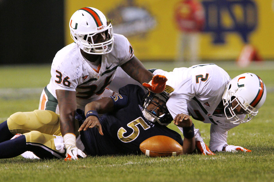 Miami linebacker Gionni Paul (36) and defensive back Deon Bush (2) stop Notre Dame quarterback Everett Golson (5) during a NCAA college football game on Saturday, Oct. 6, 2012, at Soldier Field in Chicago. (James Brosher/South Bend Tribune)