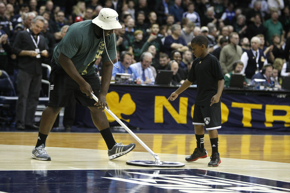 A youngster points out a missed spot on the floor as Notre Dame football captain Kapron Lewis-Moore, left, helps dry the court during a break in the action of a NCAA men's basketball game on Thursday, Nov. 29, 2012, at the Purcell Pavilion at Notre Dame. (James Brosher/South Bend Tribune)