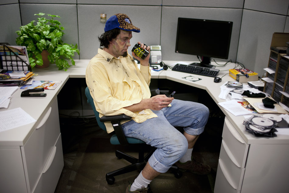 Zombie actor Duncan Krostue checks his phone as he sits in an office cubicle between takes during a promotional video shoot on Wednesday, Dec. 5, 2012, at the WNIT studios in downtown South Bend. (James Brosher/South Bend Tribune)
