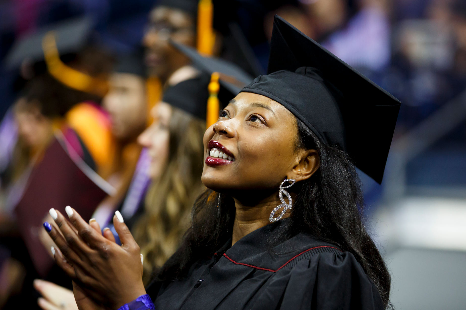 A graduate watches the ceremony on a video board during the IU South Bend Commencement at the University of Notre Dame on Tuesday, May 7, 2019. (James Brosher/Indiana University)