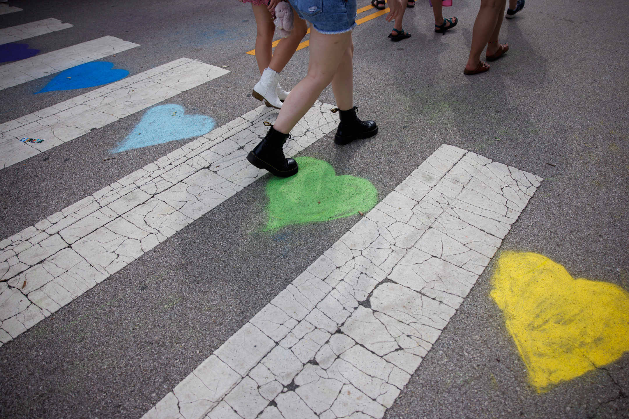 People walk over a crosswalk adorned with hearts during Bloomington Pridefest on Kirkwood Avenue on Saturday, Aug. 26, 2023. (James Brosher/Indiana University)